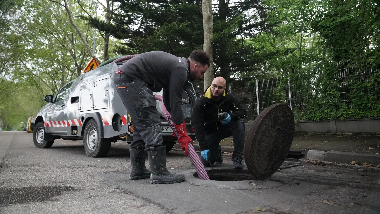 Deux techniciens EasyFix débouchent un regard d'évacuation avec le tuyau du camion hydrocureur